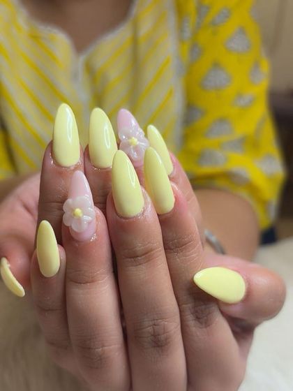 A full view of the sunny yellow manicure with 3D floral accents.