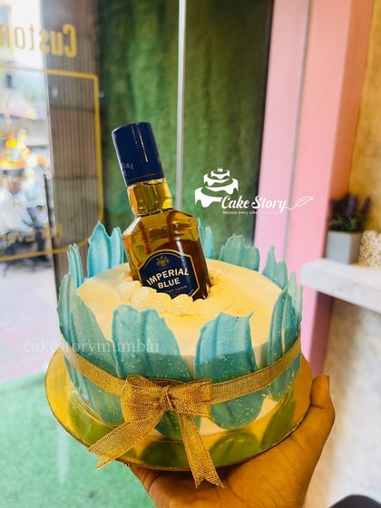 Holding up the Imperial Blue whiskey cake, which is decorated with blue accents and a gold ribbon.