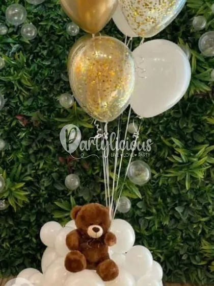 A simple and sweet teddy bear bouquet. This arrangement, with a small bear sitting on a cloud of white balloons and holding a bunch of gold and confetti balloons, is a perfect gift or centerpiece for a baby shower.