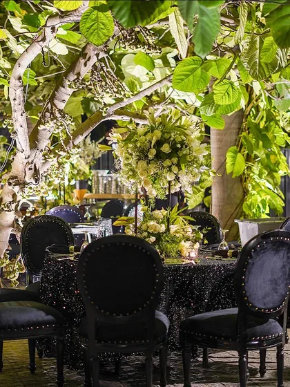 A seating area under a tree, with black velvet chairs and a sequined tablecloth. I love incorporating natural elements even in the most glamorous setups.