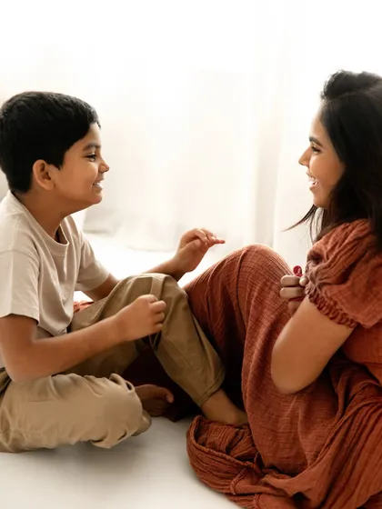 A candid moment of shared smiles. Sitting on the floor together, this mother and son's interaction feels natural, relaxed, and full of love.