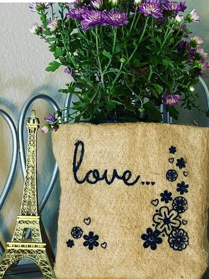 Sometimes, the simplest message is the most powerful. This jute grow bag, embroidered with the word 'love' and a floral design, turns a simple flowering plant into a heartfelt gift for someone special.