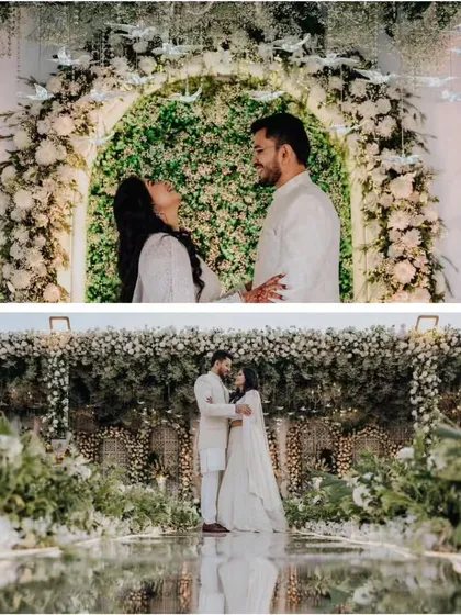 The happy couple framed by the magnificent floral arch. This shot shows how the grand scale of the white rose and greenery backdrop creates an intimate yet spectacular setting for their engagement photos.