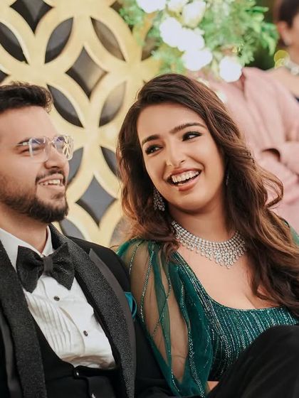 The happy couple, Pragya and Akhil, enjoying their reception. The elegant backdrop with gold geometric patterns and lush greenery was designed to create a sophisticated and warm ambiance.