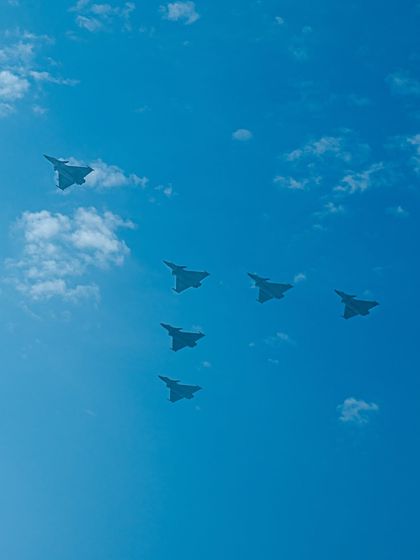 A formation of six fighter jets in a V-shape against the clouds.