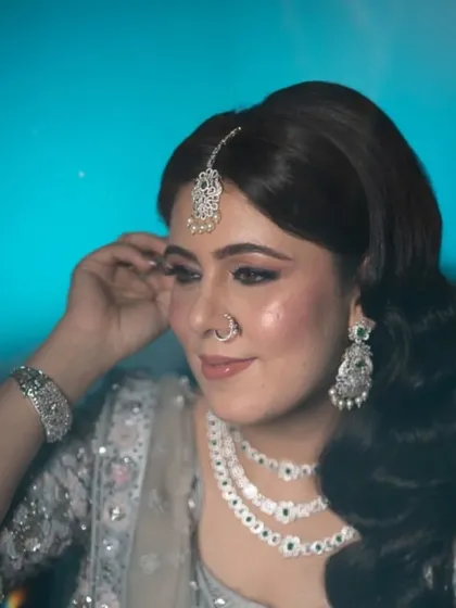 This image shows the detail of the side-swept hairstyle and the client's diamond jewelry. The hair is styled to complement the accessories and the neckline of the blouse.