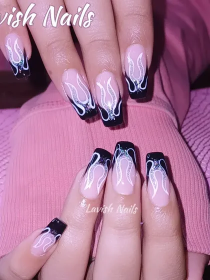 For a bold and edgy look, these long, square-tipped nails feature hand-painted black and white flames over a neutral base. The design includes a touch of glitter within the flame outline, adding depth and a subtle sparkle to this statement manicure.