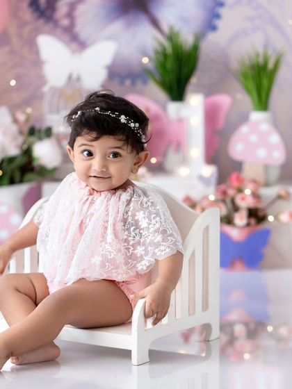 A beautiful butterfly-themed setup for a first birthday. This little one is sitting pretty on her miniature bed.