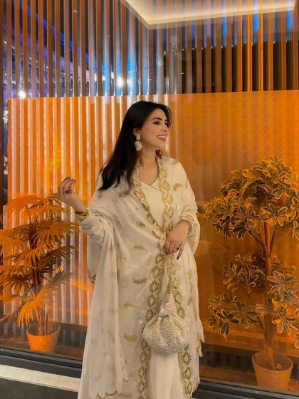 A joyful, smiling shot in the white and gold Anarkali. This conveys the feeling of wearing the outfit, making it more appealing for festive occasions.