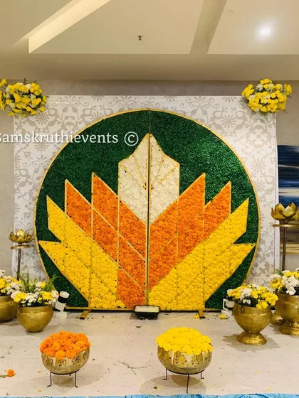 A unique backdrop featuring a large lotus motif created with yellow, orange, and white marigold petals. This design is perfect for traditional ceremonies like Haldi or a naming ceremony.