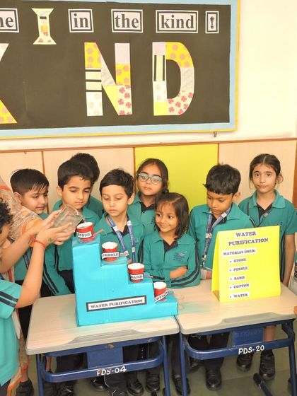 A teacher guides students through the steps of a water purification model. We foster a collaborative learning environment where students can ask questions and explore scientific processes together.