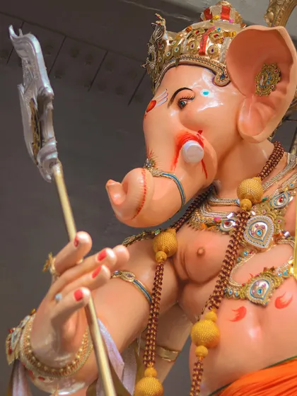A side profile of a majestic Ganesh idol, focusing on the artistry and the powerful presence it commands during the procession.