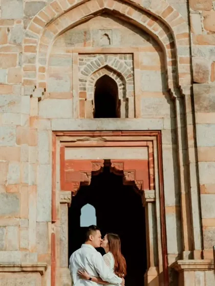 A couple shares a kiss within the grand archway of a historic monument in Delhi. This image perfectly frames their love within the timeless beauty of the location.