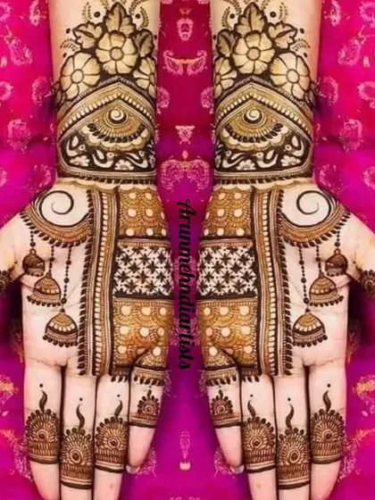 This design highlights beautiful hanging jhumka motifs on the palms. The combination of star-like jaal work and floral bands on the wrist creates a very festive look.