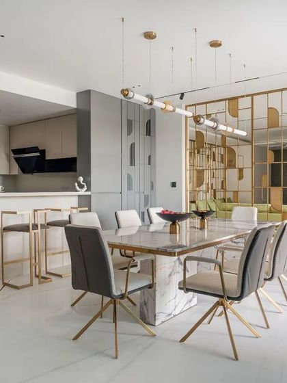 An open-concept layout connecting the kitchen, dining, and living areas. A custom brass-detailed partition provides a visual screen while allowing light and conversation to flow freely, making the space perfect for entertaining.