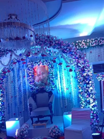 A beautiful darbar decoration with a floral arch made of purple and white flowers. The blue lighting enhances the spiritual and calming mood of the event.