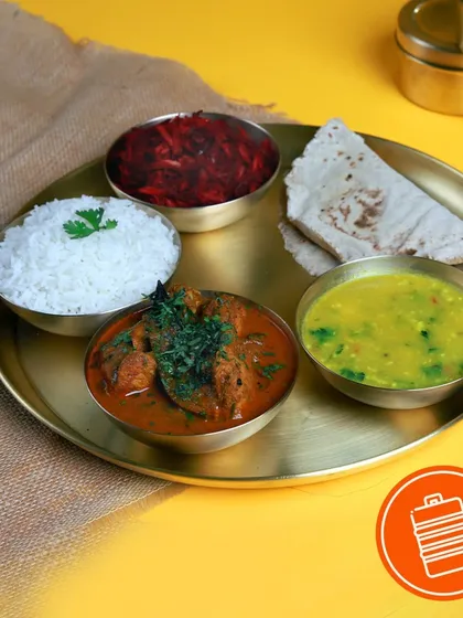 A complete meal featuring a hearty chicken curry, dal, rice, bhakri, and beetroot salad. It's a perfect example of a wholesome and satisfying non-veg thali.