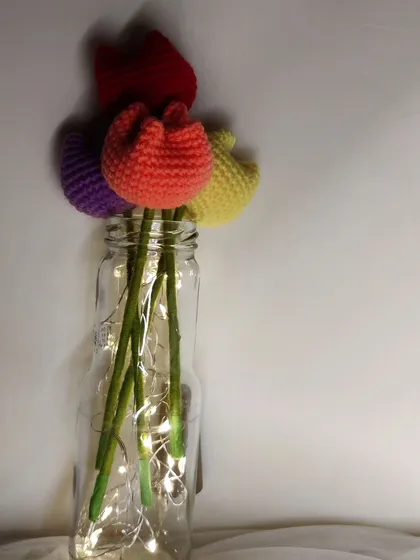 A simple and elegant arrangement of colorful crochet tulips in a glass jar with fairy lights. This shows how you can easily create a Pinterest-worthy decor piece for your room.