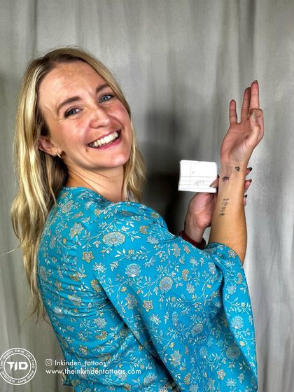 A happy client from Wales showing off her new tattoos, including the Hindi word 'Shanti' (peace).