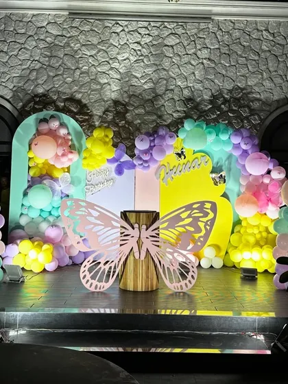 The full view of our enchanting butterfly party stage. The combination of pastel balloons, arched backdrops, and the central butterfly prop makes for a perfect cake-cutting ceremony.