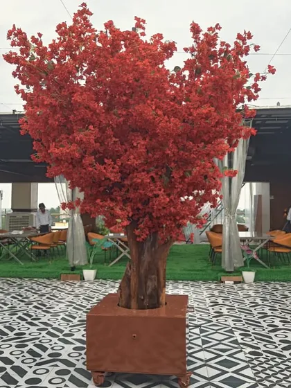 A magnificent artificial red blossom tree stands as the centerpiece of this rooftop restaurant. This statement piece adds a dramatic pop of color and sophistication, perfect for creating a memorable ambiance for events and dining.