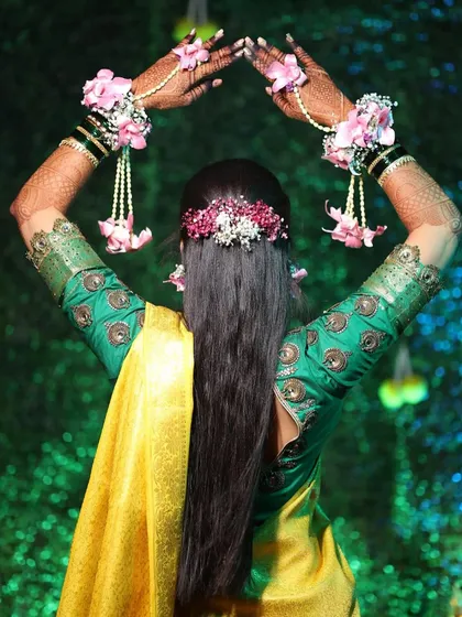 A creative shot showing the back of the Haldi hairstyle. The floral hairpiece and matching hand jewelry create a cohesive and beautiful look.