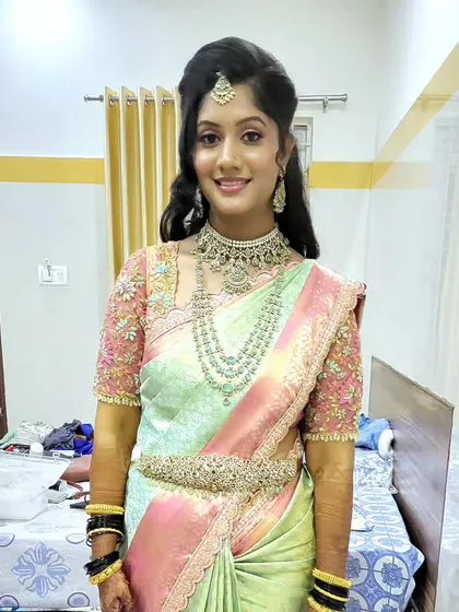 A reception look for bride Lavanya in a pastel green and pink silk saree. The spot draping was done to create a soft yet structured silhouette that complemented her diamond jewelry.