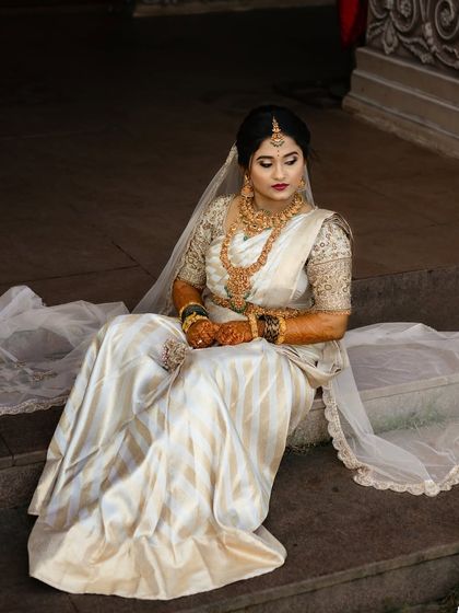 A bride in a white and gold striped saree with a sheer veil. The look is both traditional and modern, perfect for a Christian-Indian wedding.