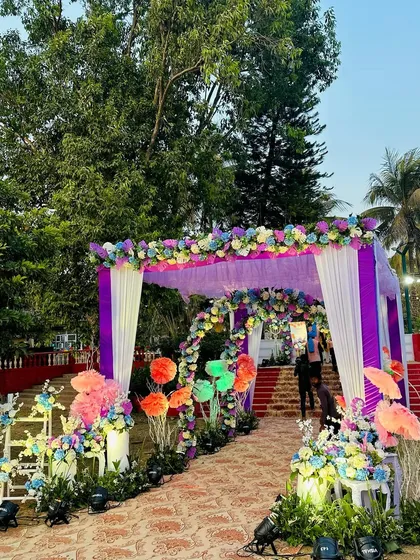 A vibrant entrance for a Haldi ceremony, using a mix of purple, blue, and orange flowers to create a festive and colorful walkway.