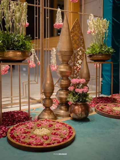 A corner decorated with traditional brass spires, floral rangolis, and hanging flower strings. This shows my expertise in creating authentic, traditional Indian decor.