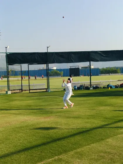A player practices taking a catch with the nets in the background, part of our daily fielding drills.