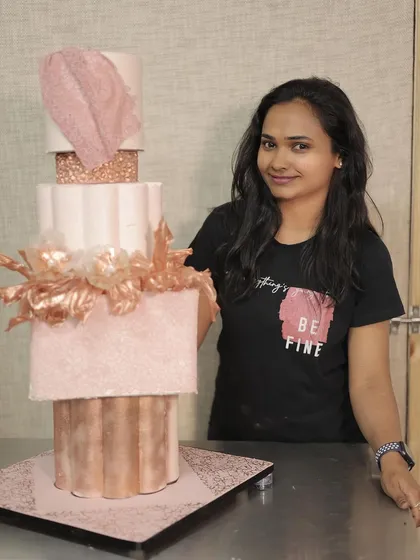 Me posing with a stunning rose gold multi-tier wedding cake I designed.