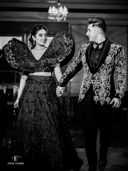 A stylish black and white shot of Muskan and Dhruv making their entrance. The bride's dramatic, high fashion lehenga is the star of this shot, showcasing our eye for capturing unique bridal wear.