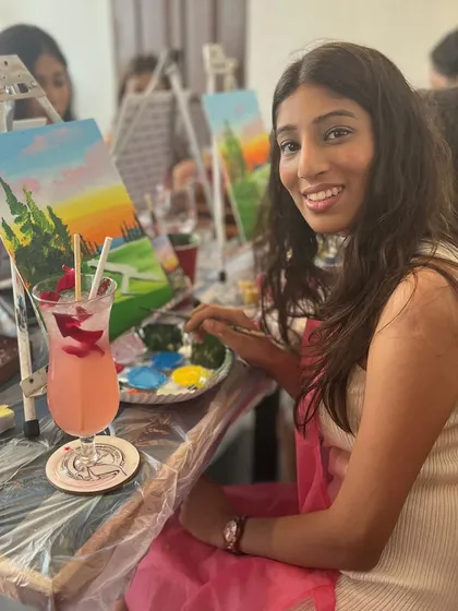 A participant enjoying a drink while painting her landscape. The sip and paint format is a great way to relax and socialize.