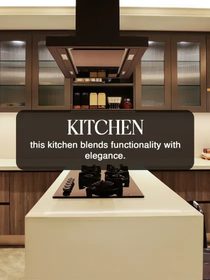 This modern kitchen blends functionality with elegance, featuring an island cooktop and a sleek chimney. The wood-finish cabinets and clean lines are hallmarks of our contemporary design aesthetic.