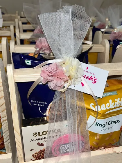 A close-up of the Women's Day gift basket, showing the "Girl Power" badge and the delicate tulle wrapping with floral accents.