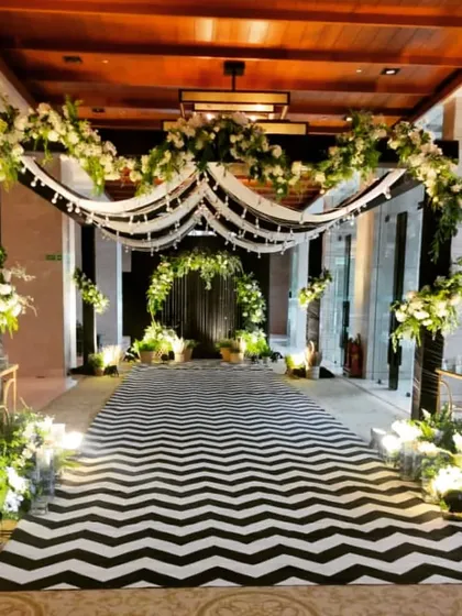 This grand entrance was designed to give guests an unforgettable first impression. Featuring a dramatic black and white chevron runner, lush white floral arches, and soft draping, it sets a tone of elegance and sophistication for any formal corporate function.