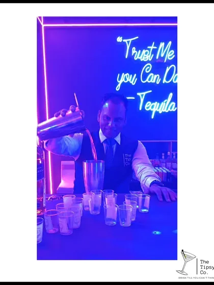 Our bartender preparing a round of tequila-flavored shots. The neon sign in the background perfectly captures the mood: 'Trust Me you Can Dance - Tequila'.