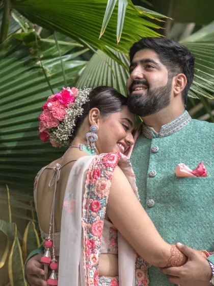 A close-up portrait capturing a tender embrace. The bride's beautiful floral hair accessory and the genuine smiles make this an incredibly warm and romantic image.