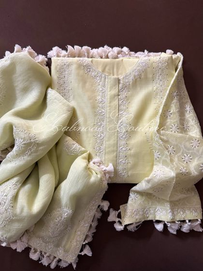 A whisper of sunshine, this pastel lemon yellow silk chanderi kurta set is perfect for daytime festivities. The ensemble is adorned with delicate Chikankari, Mukesh work, and playful tassels.