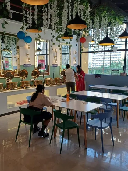 The dining area set up for guests. The combination of simple tables and colorful chairs creates a casual and friendly vibe.