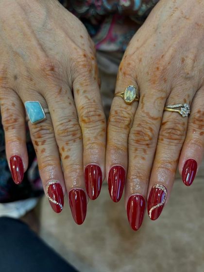 A classic red nail set with a delicate rhinestone accent, created by a student. This demonstrates their ability to create elegant and timeless looks.