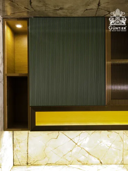 This modular kitchen unit showcases a dark green fluted veneer, paired with fluted glass and warm backlighting. It's a sophisticated and moody design for a modern kitchen.