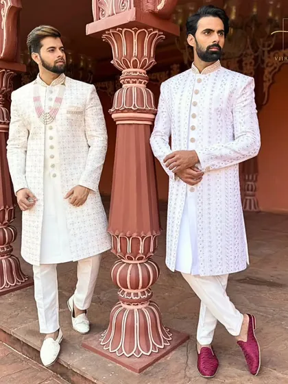 We create coordinated custom outfits for couples. Here, both grooms are in elegant white embroidered sherwanis, tailored for a perfect fit, ideal for a sophisticated wedding ceremony or a pre-wedding photoshoot.
