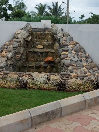 A custom-built rock waterfall feature against a boundary wall. This type of water feature can mask unwanted noise and create a soothing ambiance in any garden.