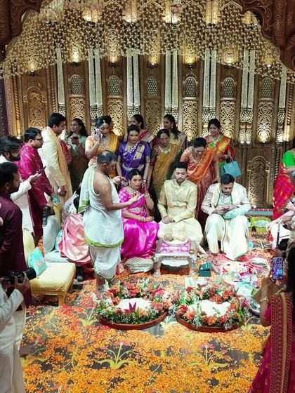 The couple performing rituals inside the magnificent 50-foot mandap. The entire space is filled with intricate carvings, floral arrangements, and traditional motifs.