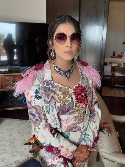 A chic and colorful look for a carnival party, featuring a textured low ponytail adorned with small pink flowers.