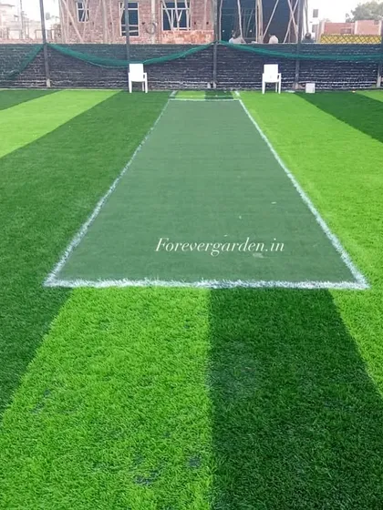 This image shows a freshly installed cricket practice pitch. The contrast between the light green running area and the darker green outfield is a popular design choice that I offer.