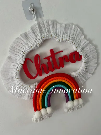 The 'Chitra' name hanging in natural light, showing the bright red name and the colorful rainbow design.