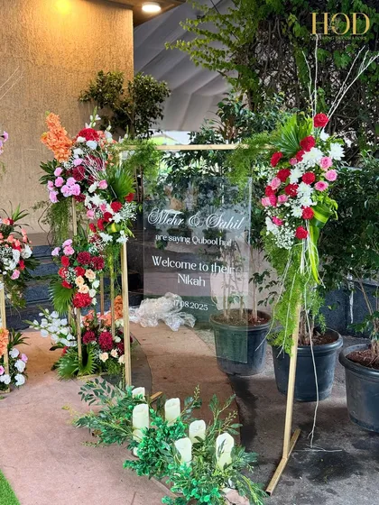 A full shot of the modern acrylic welcome sign, surrounded by lush flowers and greenery, a perfect first impression for a beautiful wedding.